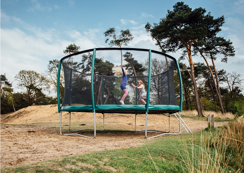 Groene Etan trampoline met veiligheidsnet in de natuur met springende kinderen